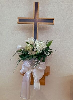 A purple cross rising out of a bouquet of white flowers
